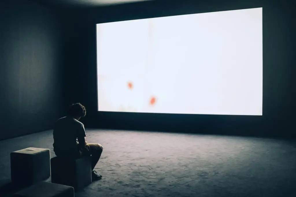 Homme seul assis dans l’obscurité face à un écran vide, illustrant pourquoi tant d’hommes souffrent en silence.