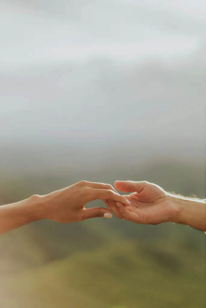 A serene moment captured as two hands reach out against a soft, blurred background.