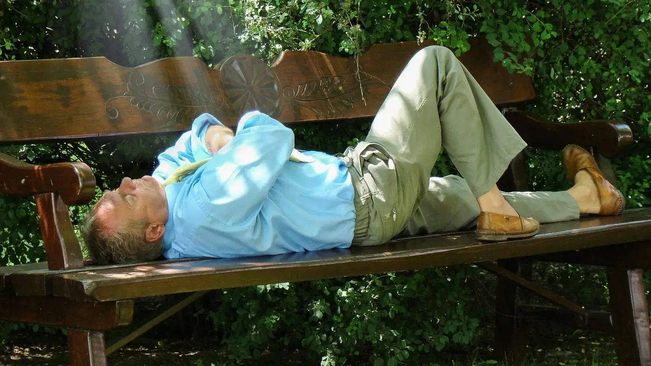 Homme se sentant seul et incompris, essayant de se retrouver, seul avec lui-même couché sur un banc, les yeux fermés, sans être endormi en pleine introspection.