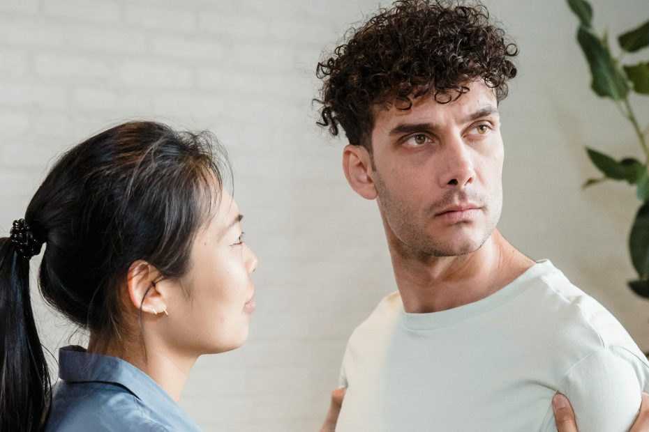Emprise émotionnelle : un homme au regard fuyant, une femme lui parle calmement — tension silencieuse dans le couple.